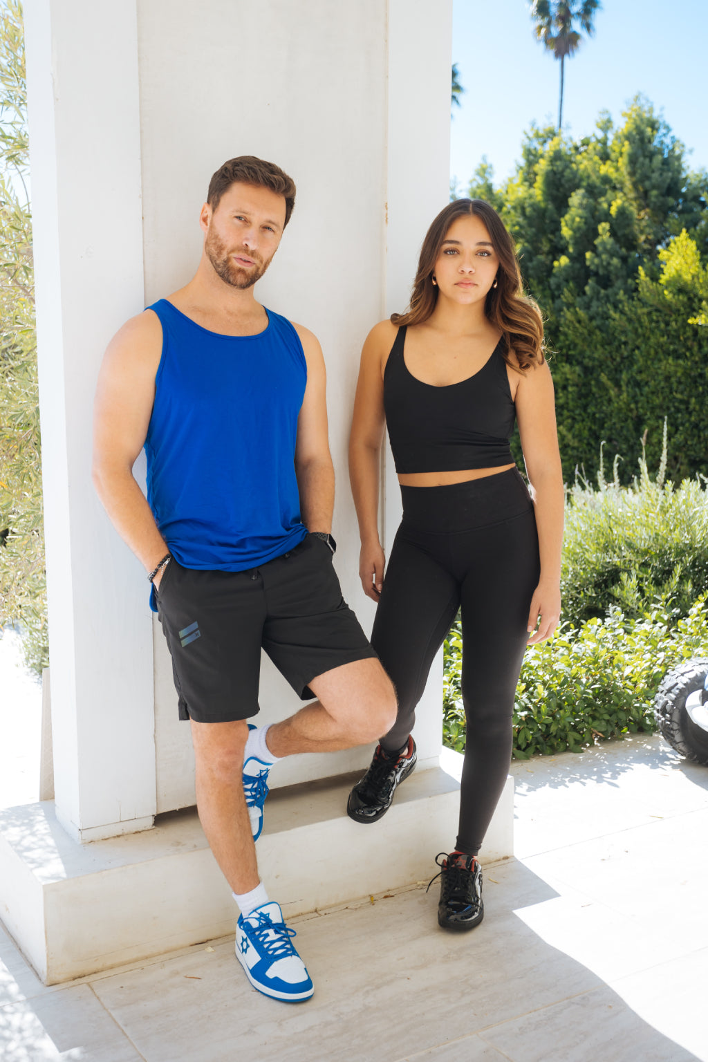 Model wearing blue and white Air Maccabees Low Top sneakers, standing outdoors beside another model.