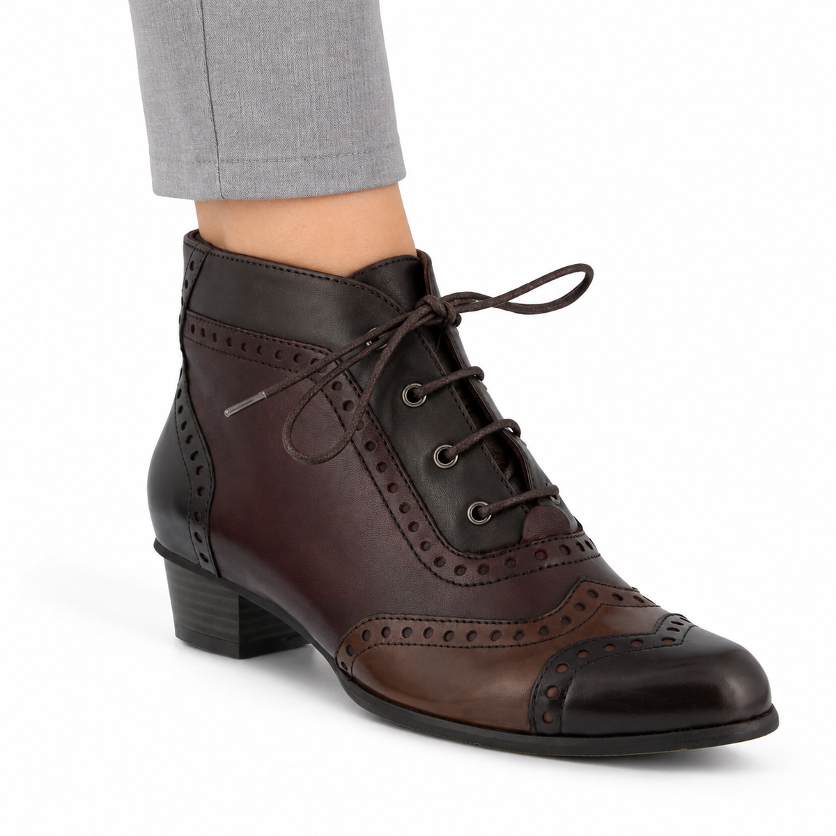 AI-generated on-model styling view of a Spring Step Heroic brown multitone brogue ankle boot, worn with light gray trousers on a white studio background.