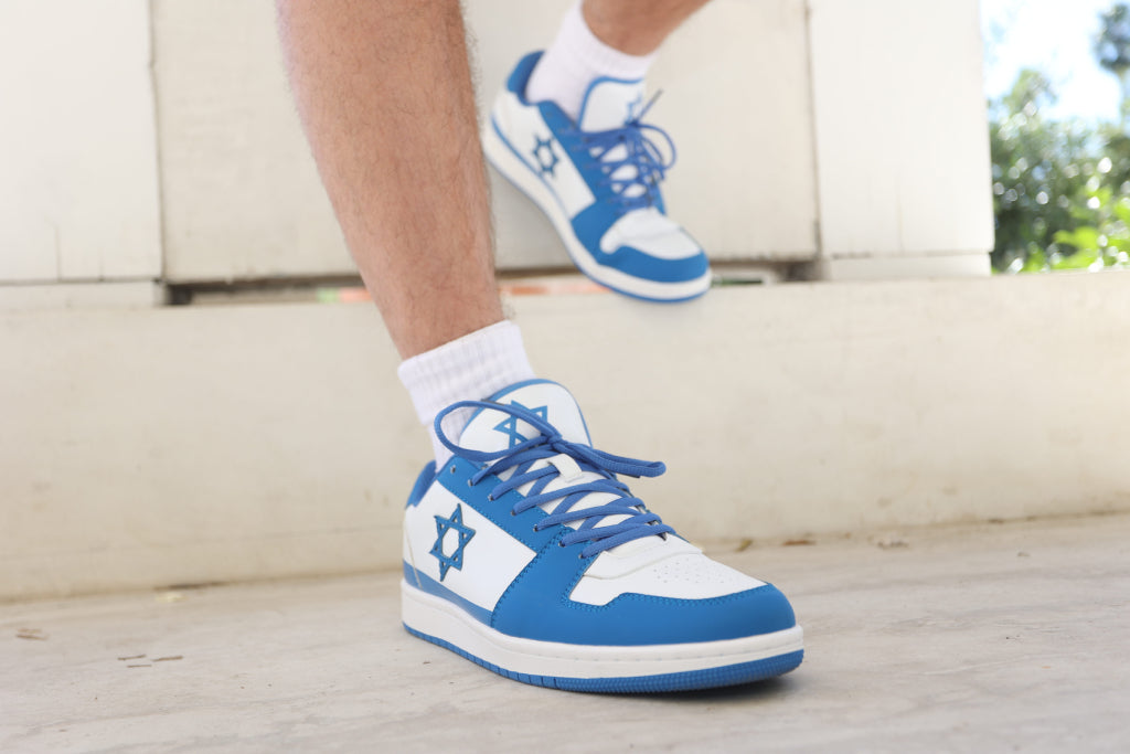 Blue and white Air Maccabees Low Top sneakers worn with white socks, outdoor close-up.