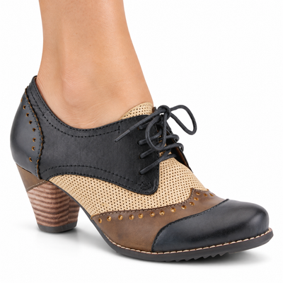 AI-generated image of an adult woman wearing the L'Artiste Bardot lace-up heeled shoe in Navy, with dark panels, taupe-brown trim, a beige perforated insert and a brown block heel, on a white background.