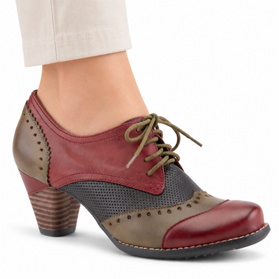 AI-generated on-model image of the L'Artiste Bardot lace-up heeled shoe in Red, with olive trim, charcoal perforated panels and a brown block heel, on a white background.