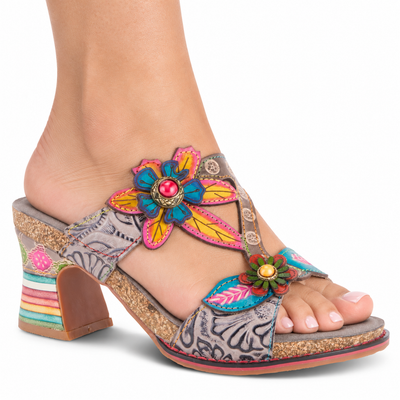 AI-generated on-model view of the L'Artiste Rossie Grey Multi sandal with floral appliques and a rainbow-banded heel on a white studio background.