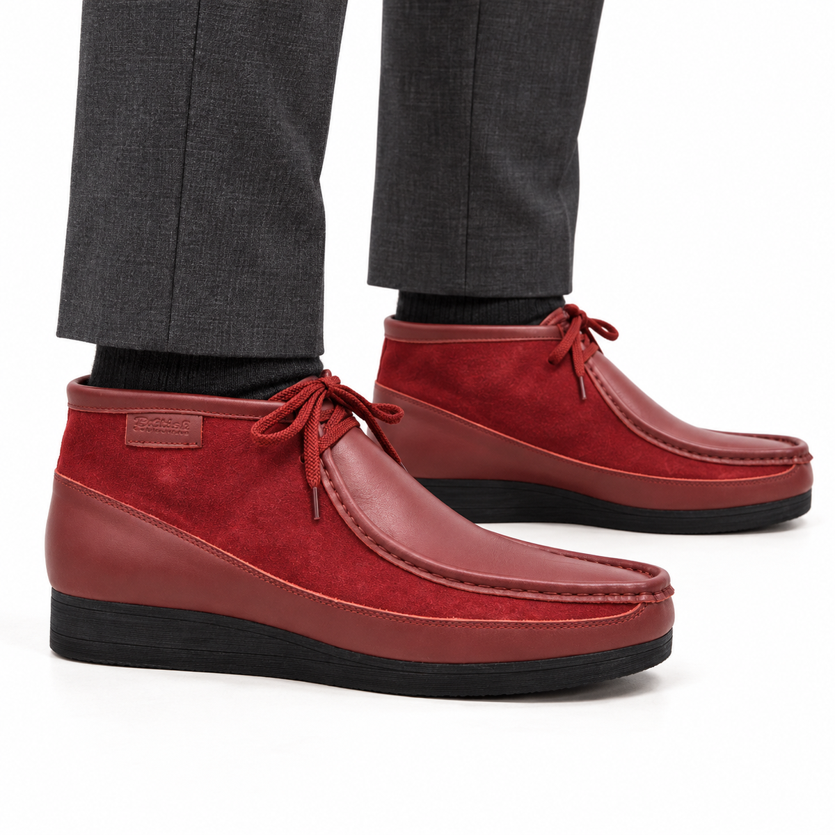 AI-generated on-model view of British Walkers New Castle Classic cherry red leather-and-suede ankle boots with charcoal trousers on a white background.