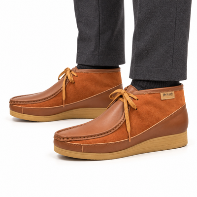 AI-generated on-model view of British Walkers New Castle Classic Cognac/Tan leather-and-suede ankle boots with charcoal trousers on a white background.