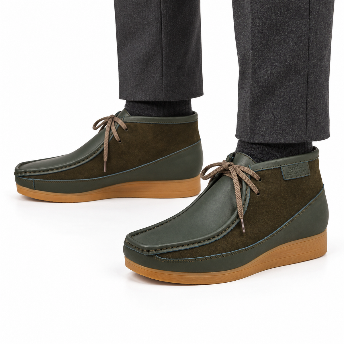 AI-generated on-model view of British Walkers New Castle Classic forest green leather-and-suede ankle boots with tan soles and charcoal trousers on a white background.