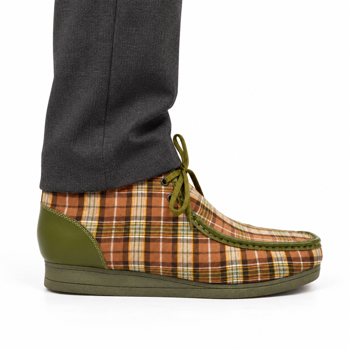 AI-generated on-model styling view of a British Walkers New Castle Limited Plaid Green Multi Plaid ankle boot, worn with charcoal trousers on a white studio background.